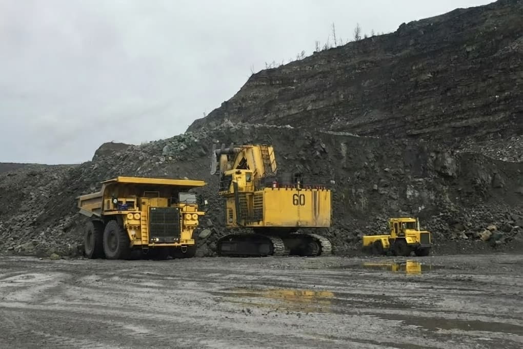 Excavator loading haul truck in open pit mine